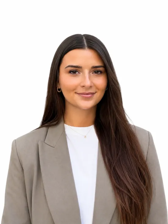 Professional headshot of a woman with long dark brown hair wearing a beige blazer and white top against a clean white background
