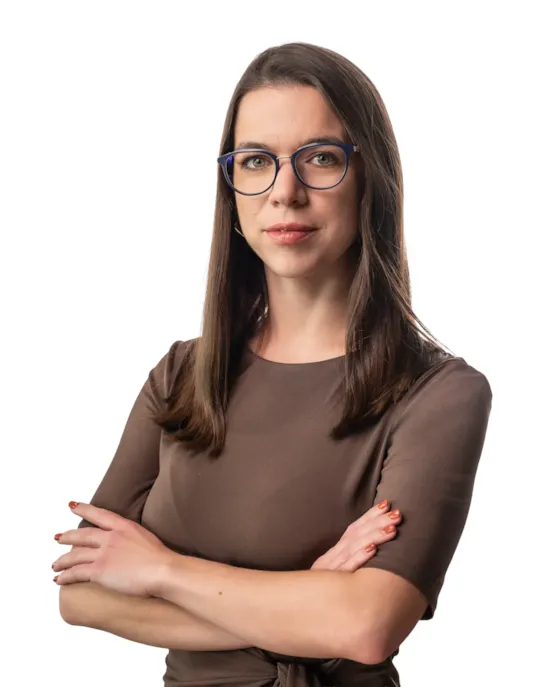 Professional female recruitment consultant with glasses, arms crossed, wearing a brown top against a neutral background
