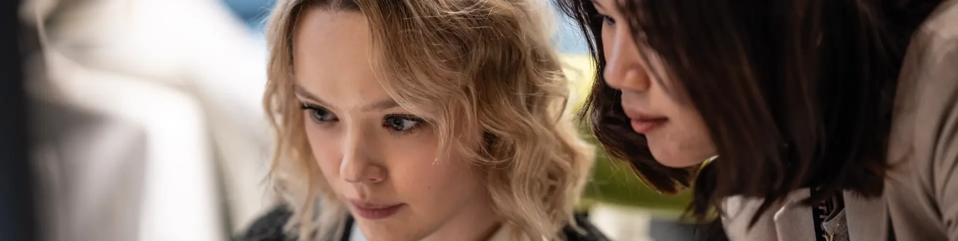 Two women closely looking at a computer screen, focused and engaged in their work.
