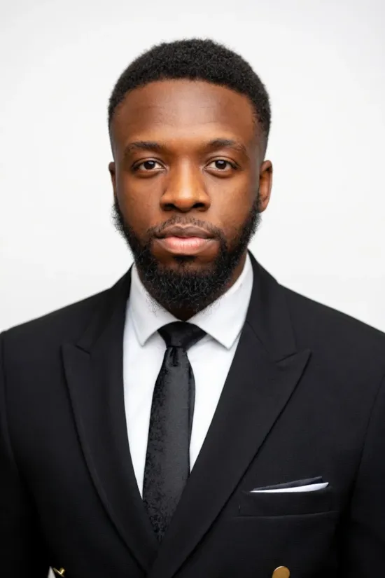 A man in a white shirt with a neutral expression, standing against a plain white background.