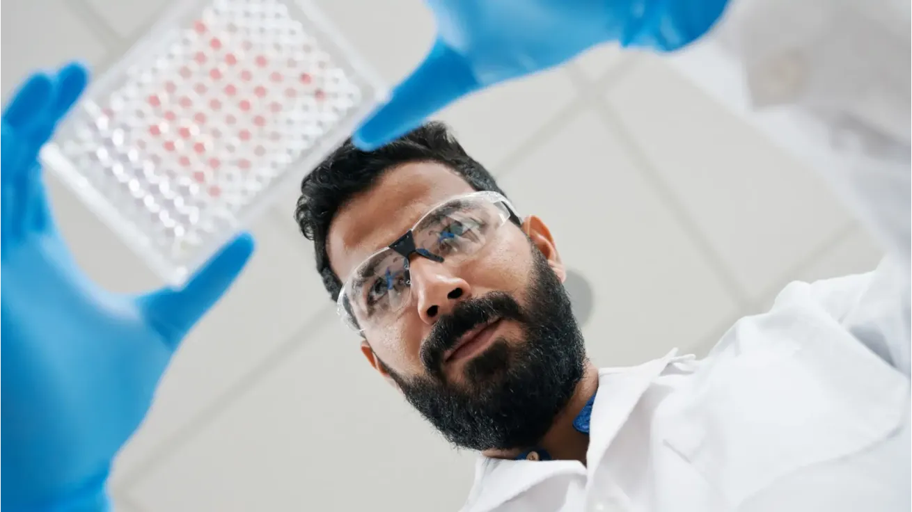 Man in lab coat holding tray of samples
